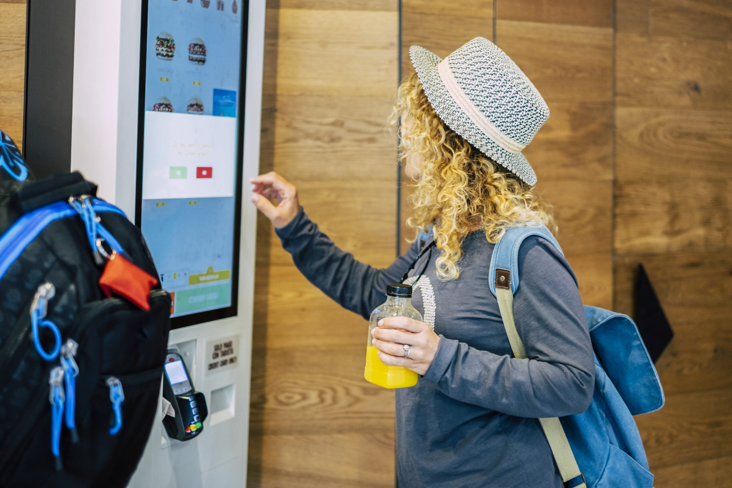 One adult woman choosing, her food in a restaurant or bar with a touch screen distributor in some fast food curly lady choosing what to eat at luch or dinner